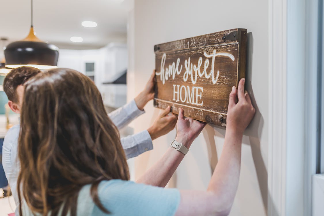 Free A Couple Holding a Wooden Home Sweet Home Wall Decoration Stock Photo