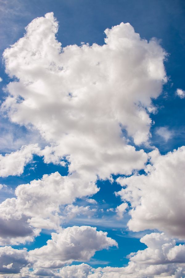 Vivas nuvens cúmulos flutuam contra um céu azul brilhante, criando uma cena natural deslumbrante.
