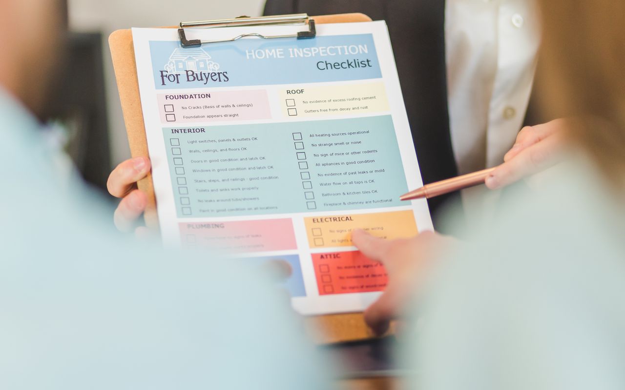 Hands with home-inspection checklist on clipboard