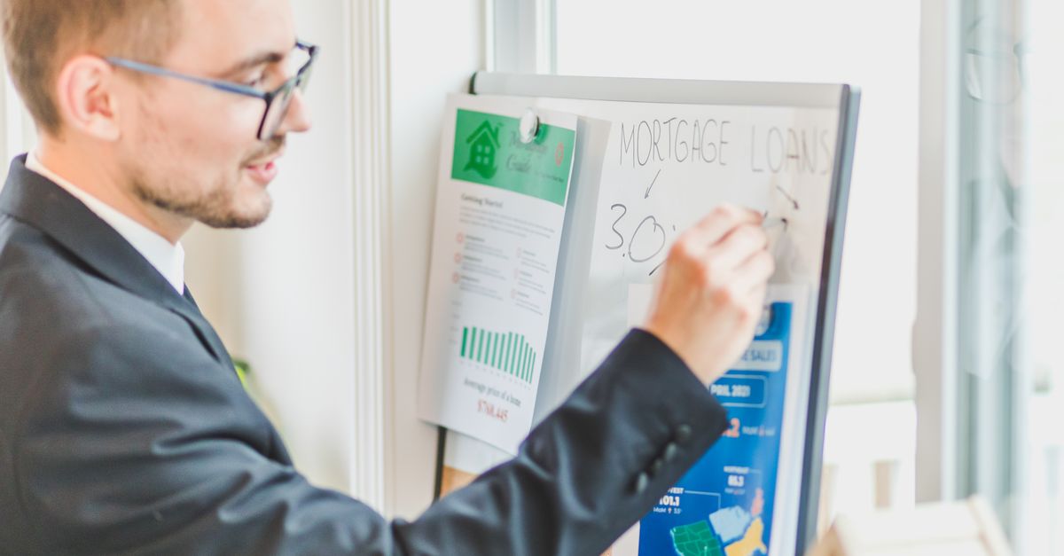 Photo by RDNE Stock project Businessman in suit writes on whiteboard displaying mortgage loan rates during a real estate meeting.