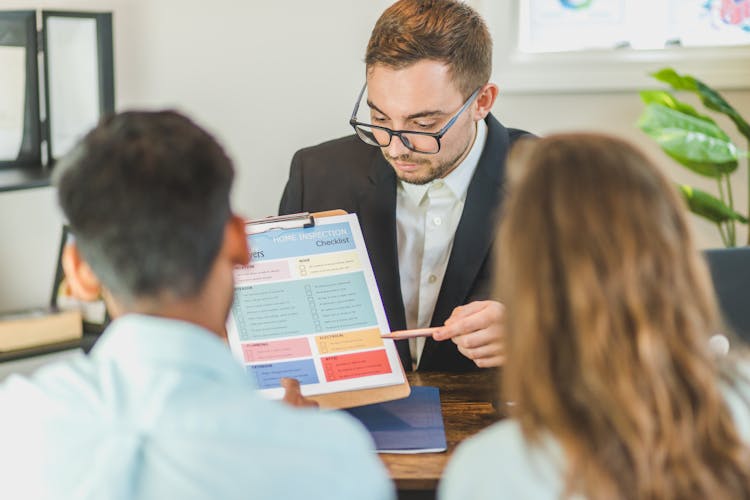 Real Estate Agent Discussing And Explaining A Document To A Couple