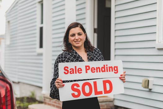 A real estate agent holding a 'Sale Pending Sold' sign in front of a home.