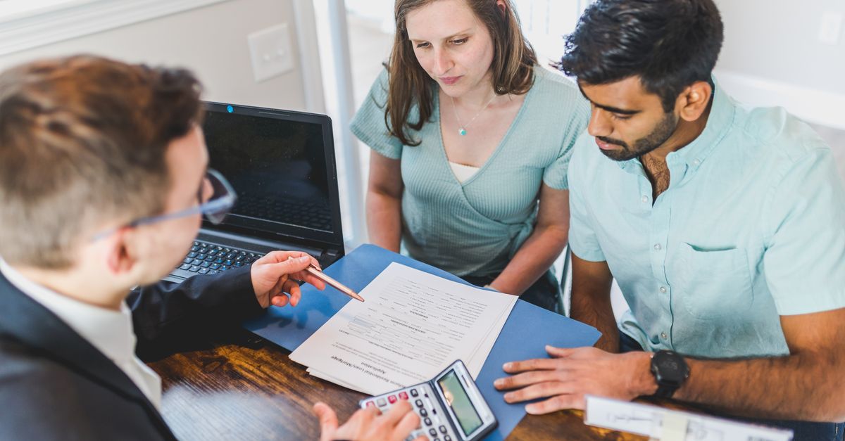 Mortgage broker reviewing amortization, term and pre-approval paperwork with clients at a Toronto office desk