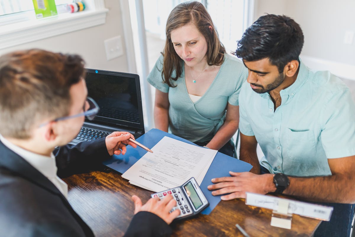 Real estate agent discussing property survey report and ownership agreement with couple in office