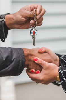 Close-up of a handshake with a house key, symbolizing real estate transactions.