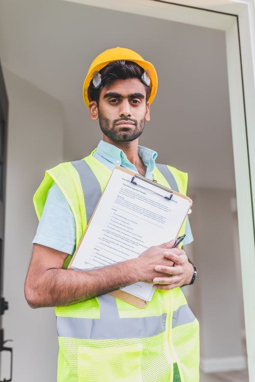 Safety compliance officer with clipboard reviewing gap between documented procedures and actual field behaviour at industrial site