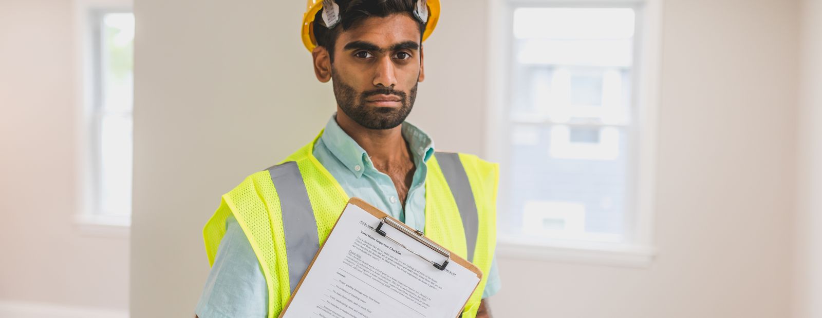 Man in a yellow hard hat holding a clipboard