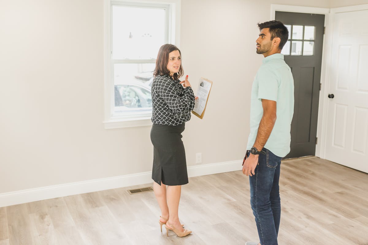 Property buyer with real estate agent checking house during viewing and survey decision
