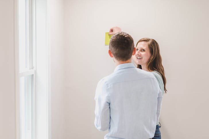 Back View of Man Beside a Woman Choosing Paint Color of Wall