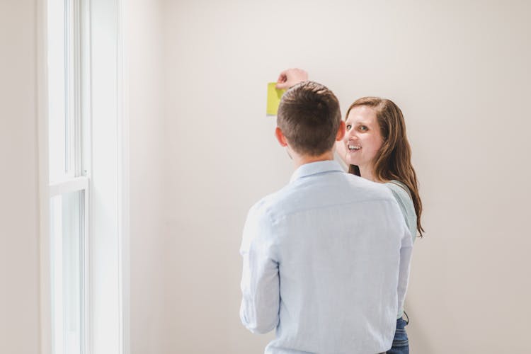 Back View Of Man Beside A Woman Choosing Paint Color Of Wall