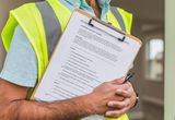 Inspector in a safety vest holding a house inspection checklist