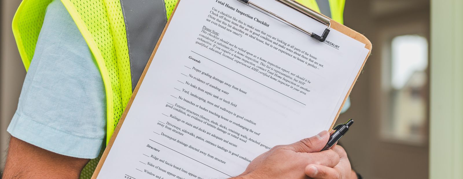 Inspector in a safety vest holding a house inspection checklist