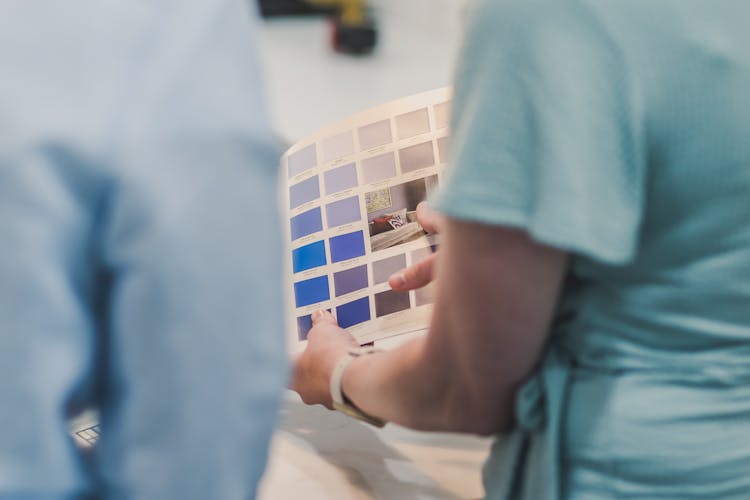 A Person Pointing The Colored Catalog She Is Holding