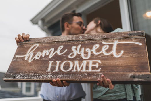 A couple embracing while holding a 'Home Sweet Home' sign, symbolizing new beginnings.