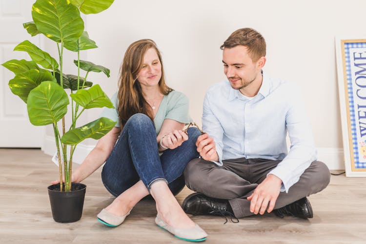 Man And Woman Sitting On The Floor While Holding Keys