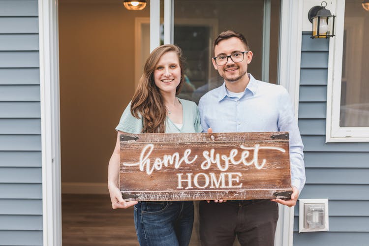 Couple Holding A Wooden Home Sweet Home Sign