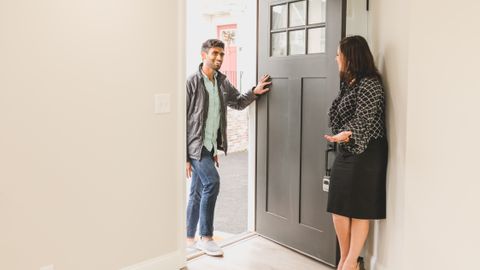 Real estate agent greeting a client at the entrance of a new home, symbolizing a welcoming embrace for potential buyers.