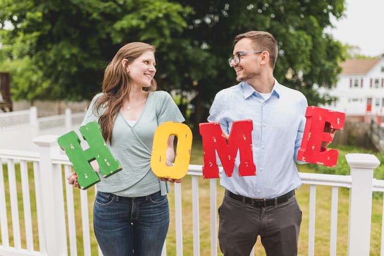 Couple Holding A Wooden Home Sign