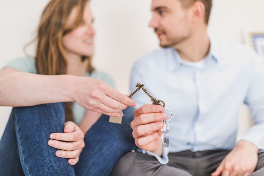A young couple sitting together exchanging keys, symbolizing new home ownership