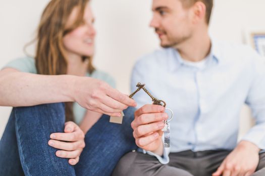 A young couple sitting together exchanging keys, symbolizing new home ownership