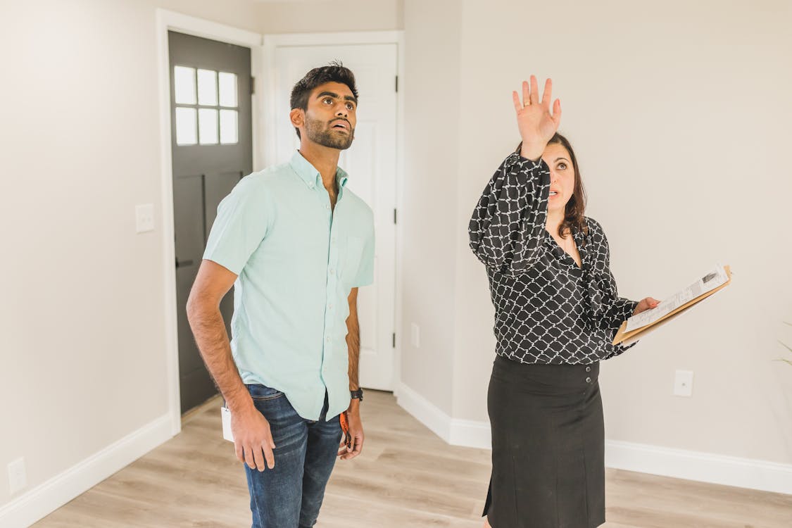 Free A Woman in Black Long Sleeves Showing the Property to the Man Stock Photo
