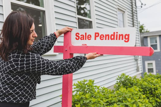 A realtor adjusting a sale pending sign outside a house for sale.