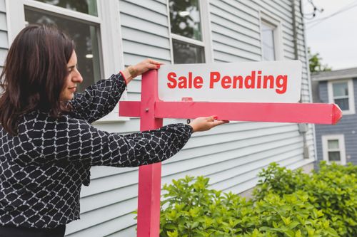 Free A realtor adjusting a sale pending sign outside a house for sale. Stock Photo