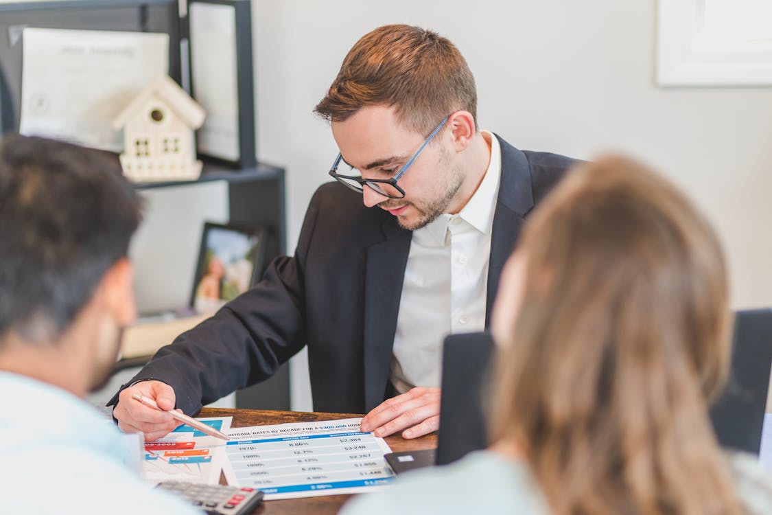 Mortgage consultant reviewing credit score reports with a couple, advising them on securing a real estate loan.