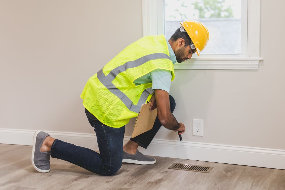 Contractor checking flooring during a home inspection to assess repair or restoration needs