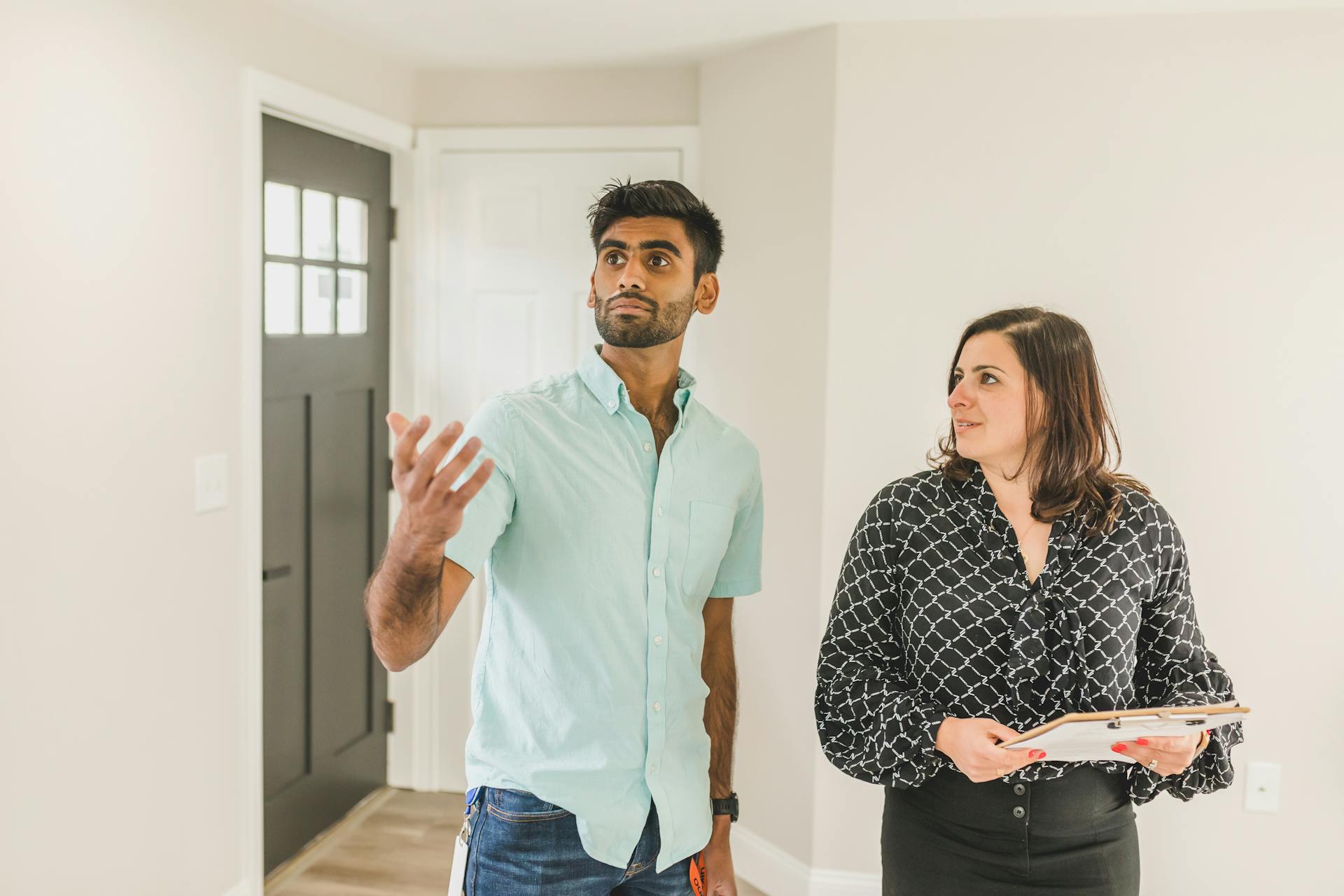 A real estate agent tours a home with a potential buyer, showcasing property features.