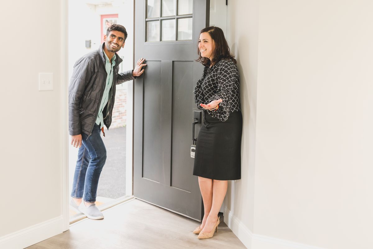 A real estate agent welcoming a client at the front door of a home