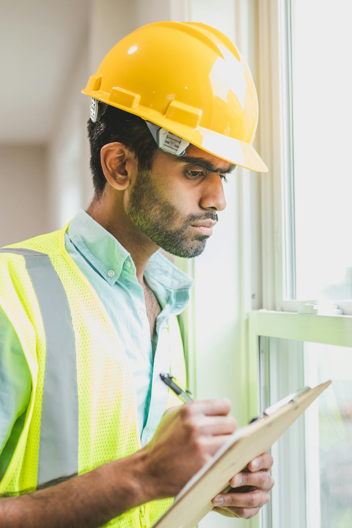 Professional construction worker examines property indoors with clipboard, ensuring safety compliance