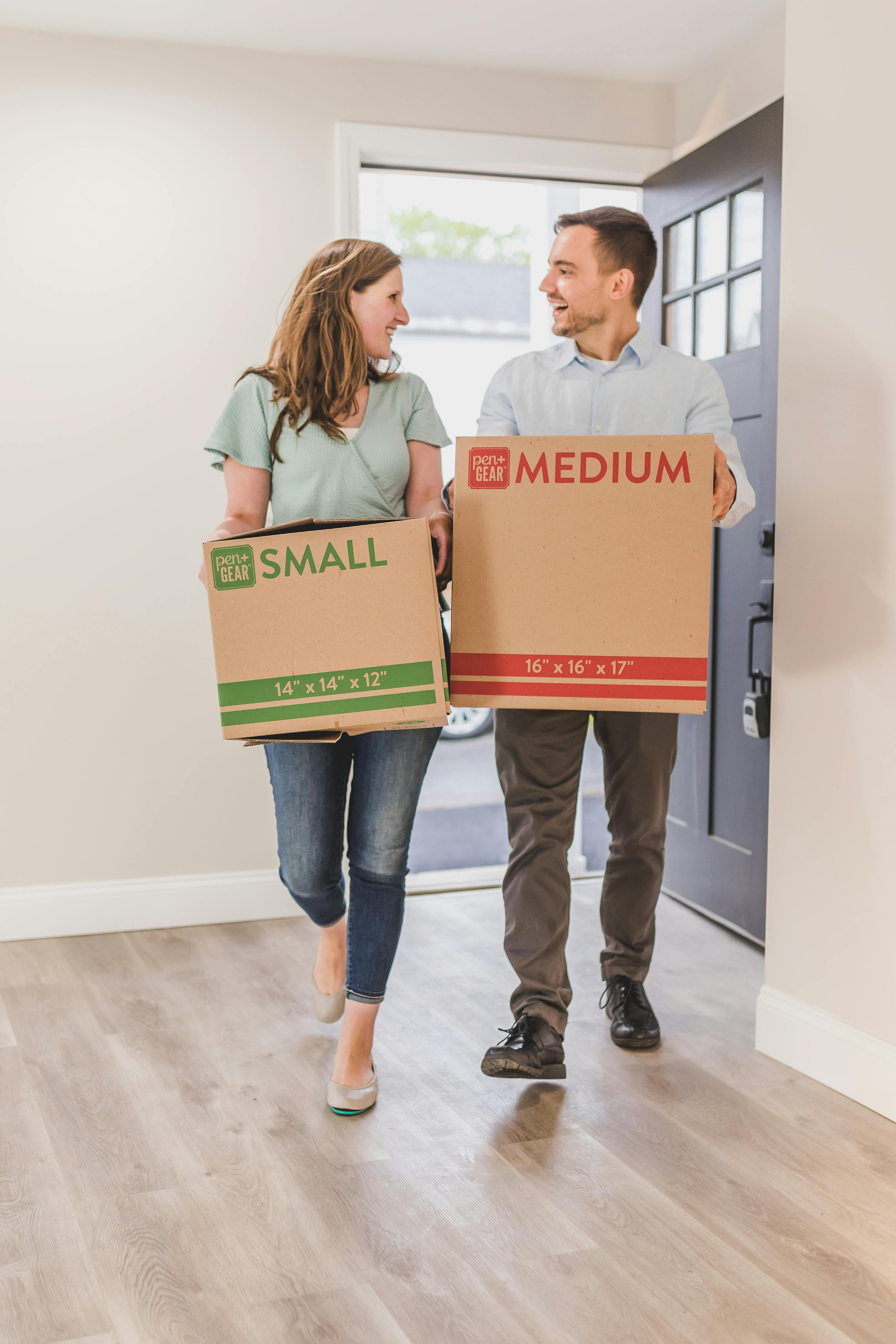 man and woman holding brown cardboard box