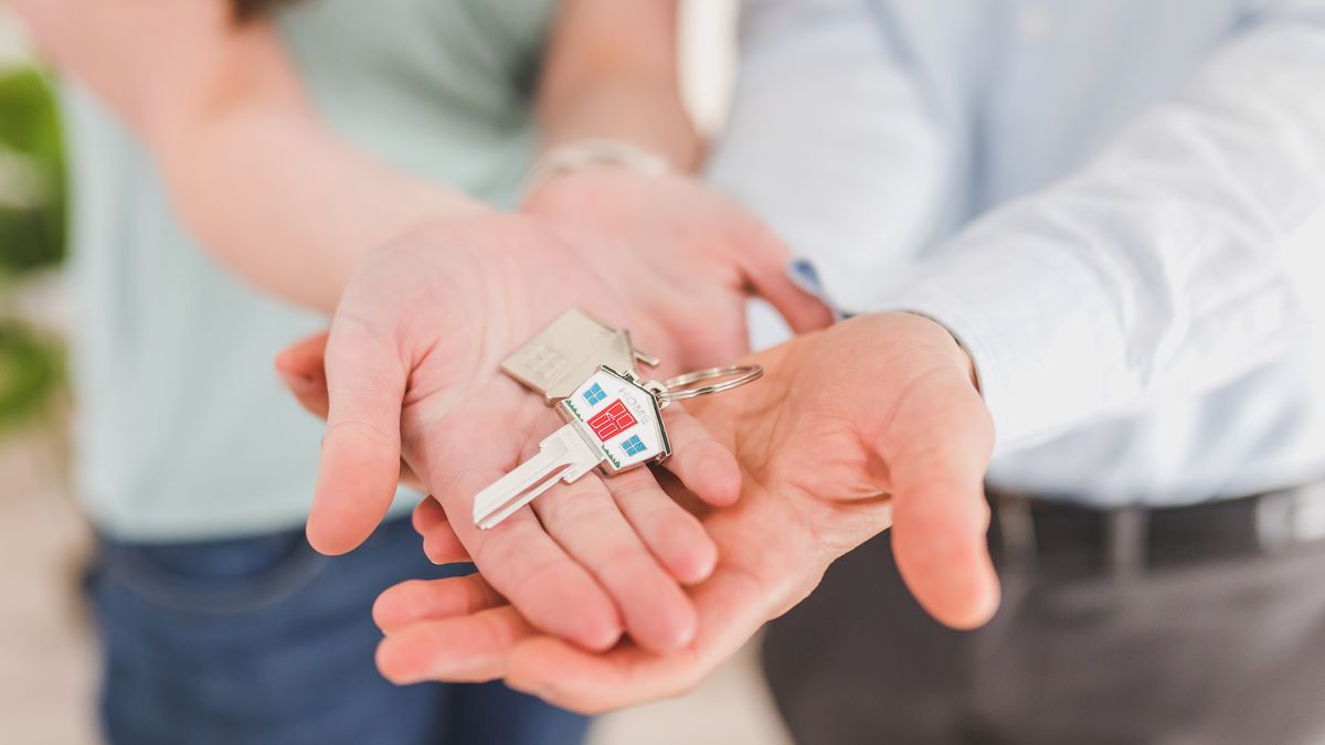 Close-up of a couple holding keys, symbolizing homeownership and investment.
