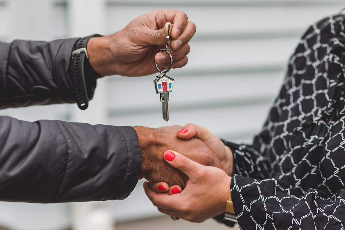 A person handing over the keys to a house to a woman.