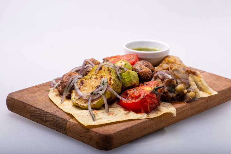 A Delicious Meal With Sliced Tomatoes And Onions On A Wooden Chopping Board