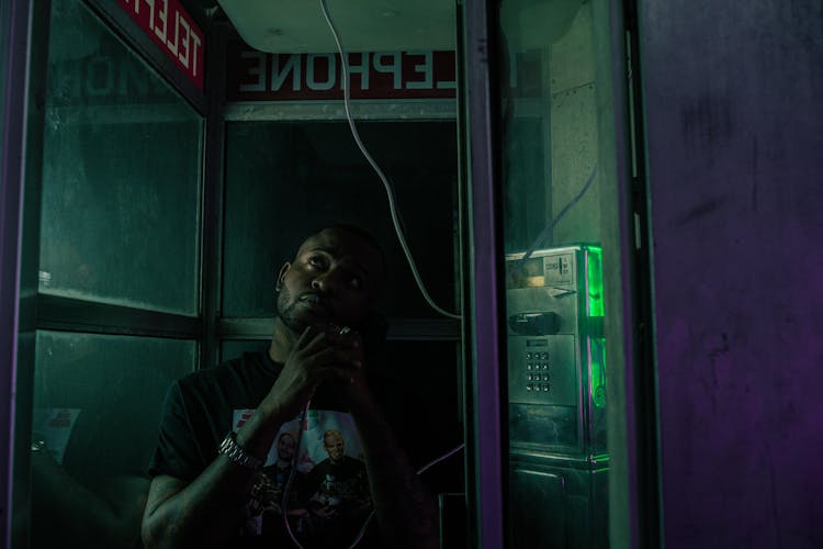 A Man Using A Telephone In A Telephone Booth