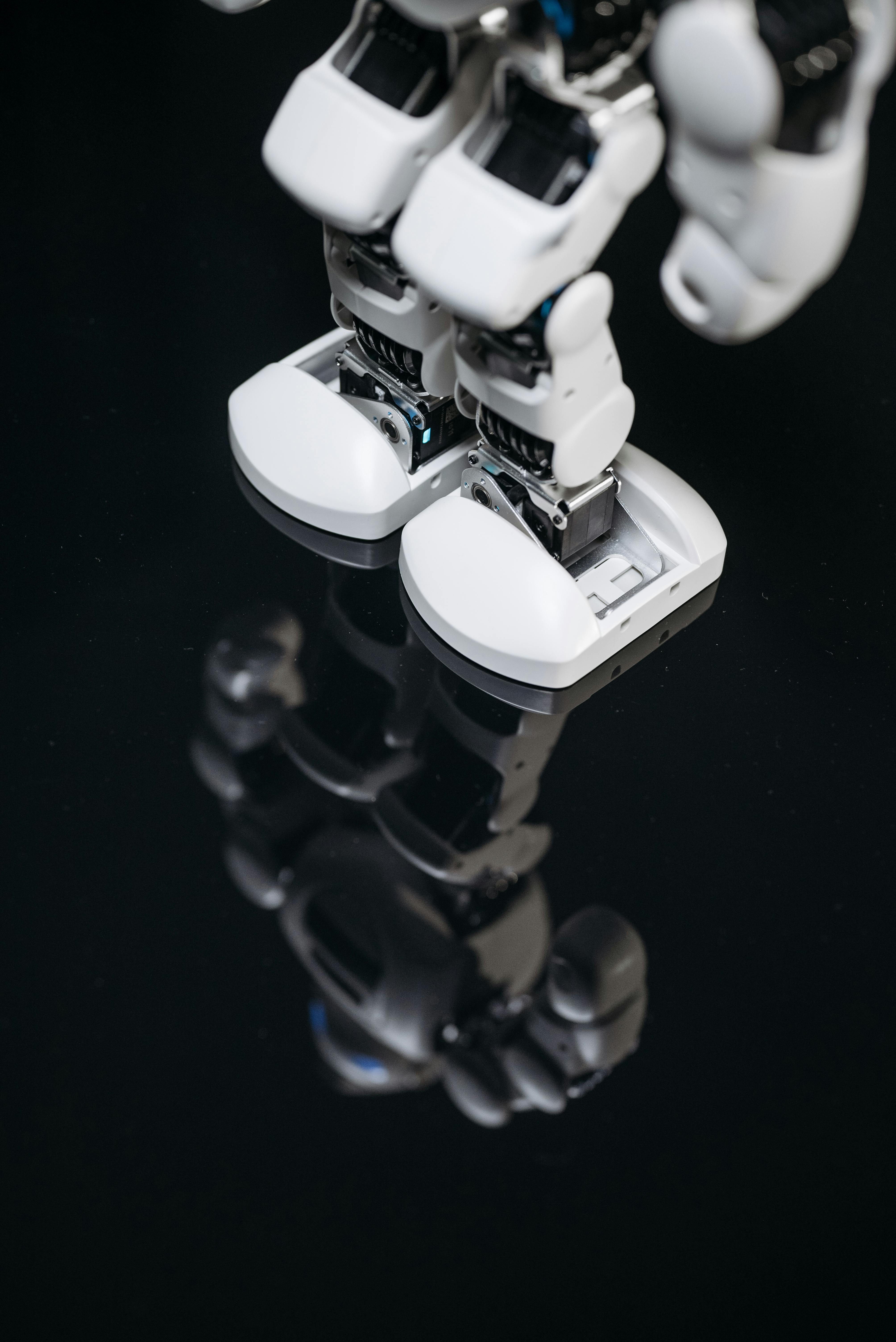 knee and feet of a white robot standing on a black shiny surface