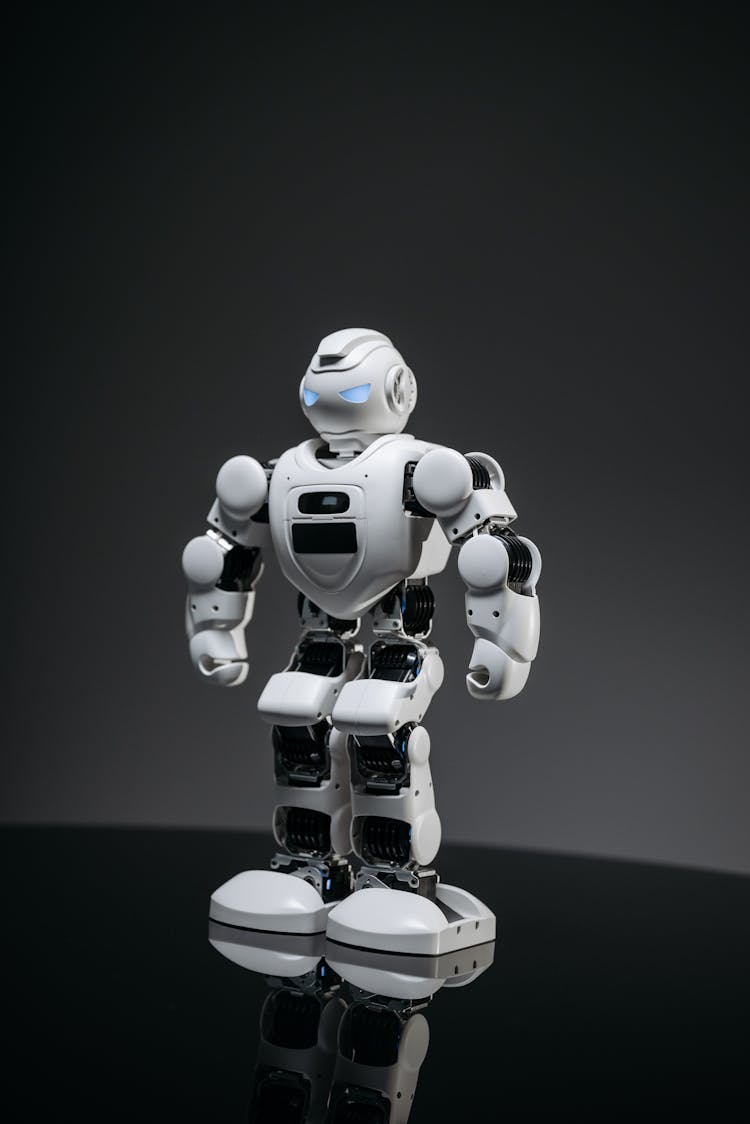 A White Robot On A Black Shiny Surface With Lighted Eyes