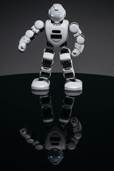 A small, futuristic robot toy stands on a reflective black surface, against a dark background.
