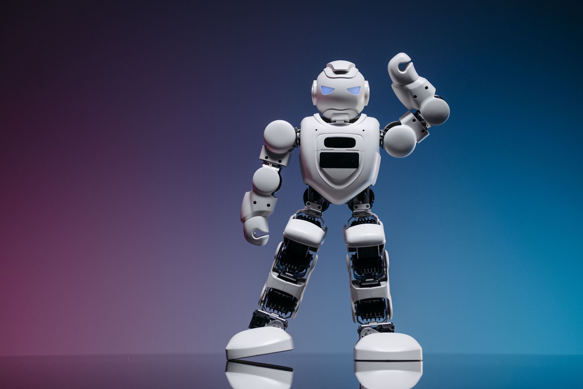 A sleek white robot in a studio setting against a gradient background, showcasing modern robotics.