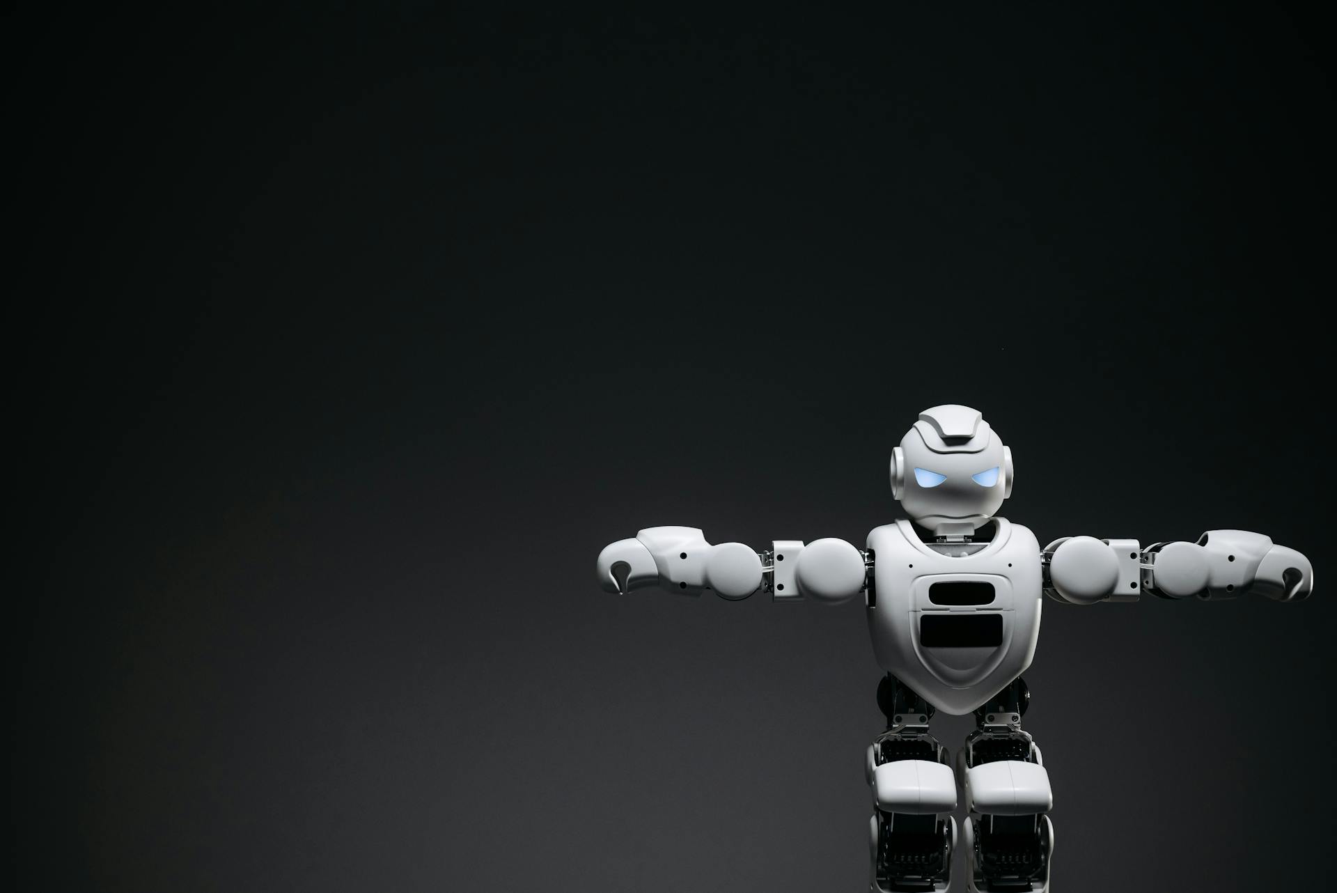 Studio shot of a humanoid robot with glowing eyes against a dark background, offering ample copyspace.