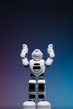 Portrait of a white humanoid robot standing with arms raised against a gradient studio backdrop.