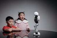 Kids Looking at White Toy Robot on the Table