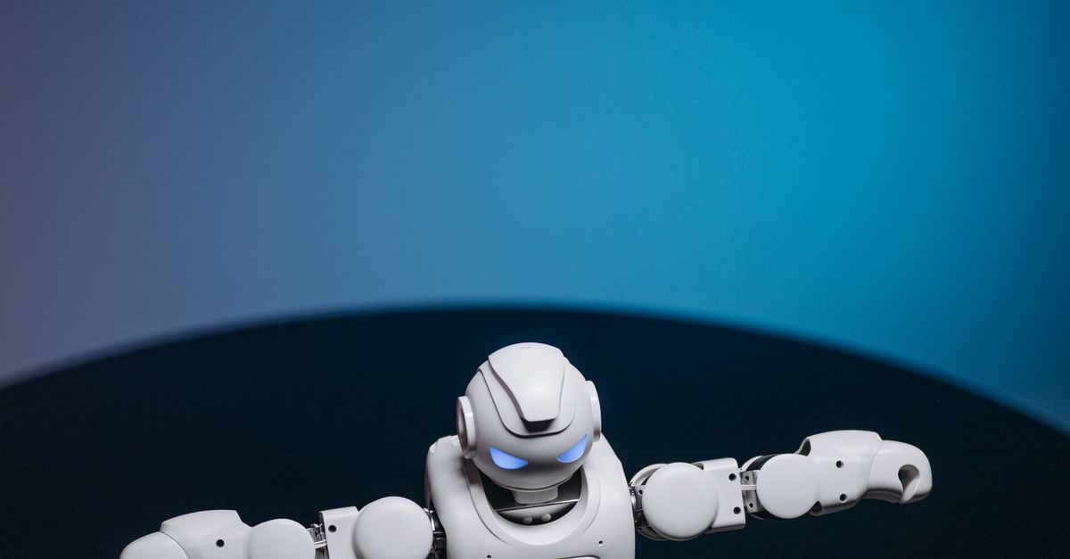 Photo by Pavel Danilyuk White toy robot with glowing eyes posed in a studio setting against a dark background.
