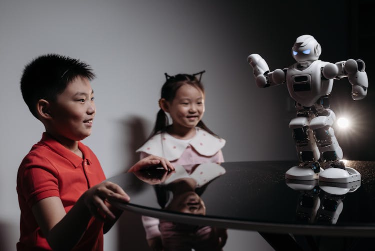 Kids Looking At White Toy Robot On The Table