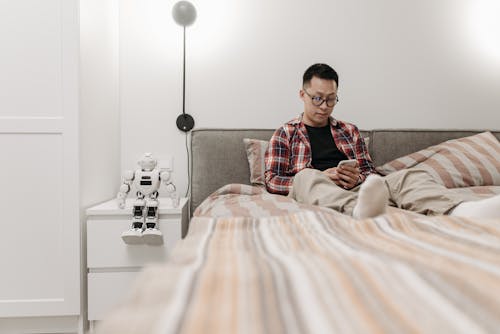 A Man Sitting on the Bed while Using Smartphone