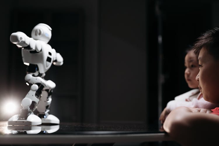 Kids Looking At White Toy Robot On The Table