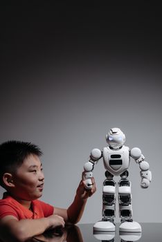 A young boy interacts with a modern white robot toy in an indoor setting, showcasing innovation and playfulness.