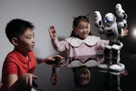 Kids Looking at White Toy Robot on the Table